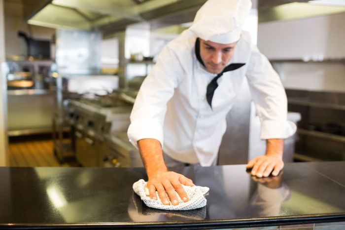 A food worker finishes cleaning and sanitizing the kitchen