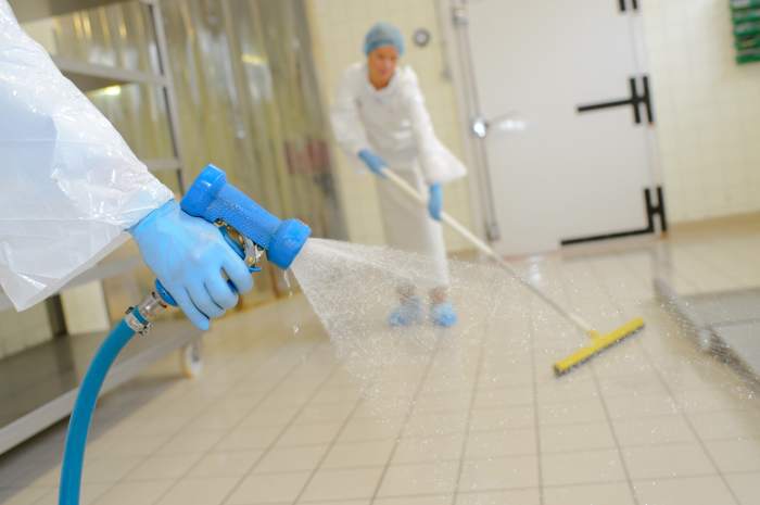 A food worker finishes cleaning and sanitizing the kitchen